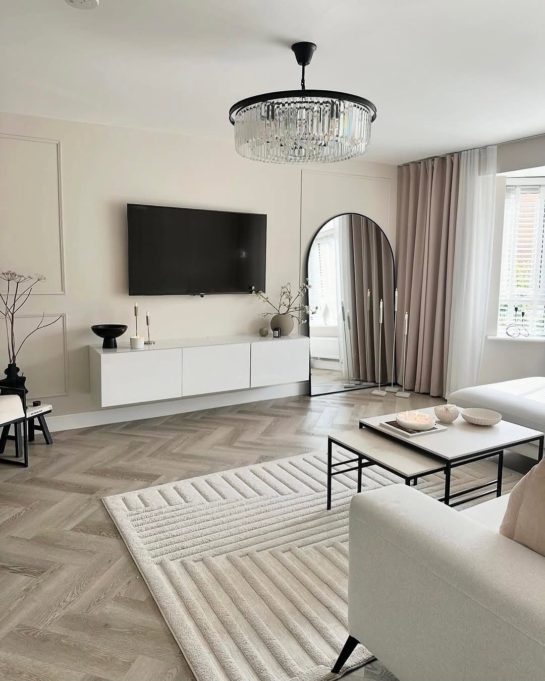 A minimalist living room featuring a white textured rug, herringbone floors, and neutral furniture.