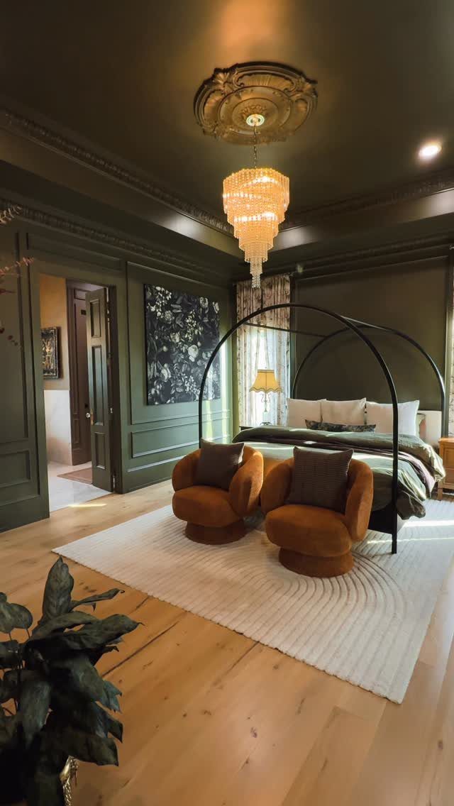 Olive green walls, ceiling, and trim surround a canopy bed and velvet armchairs.