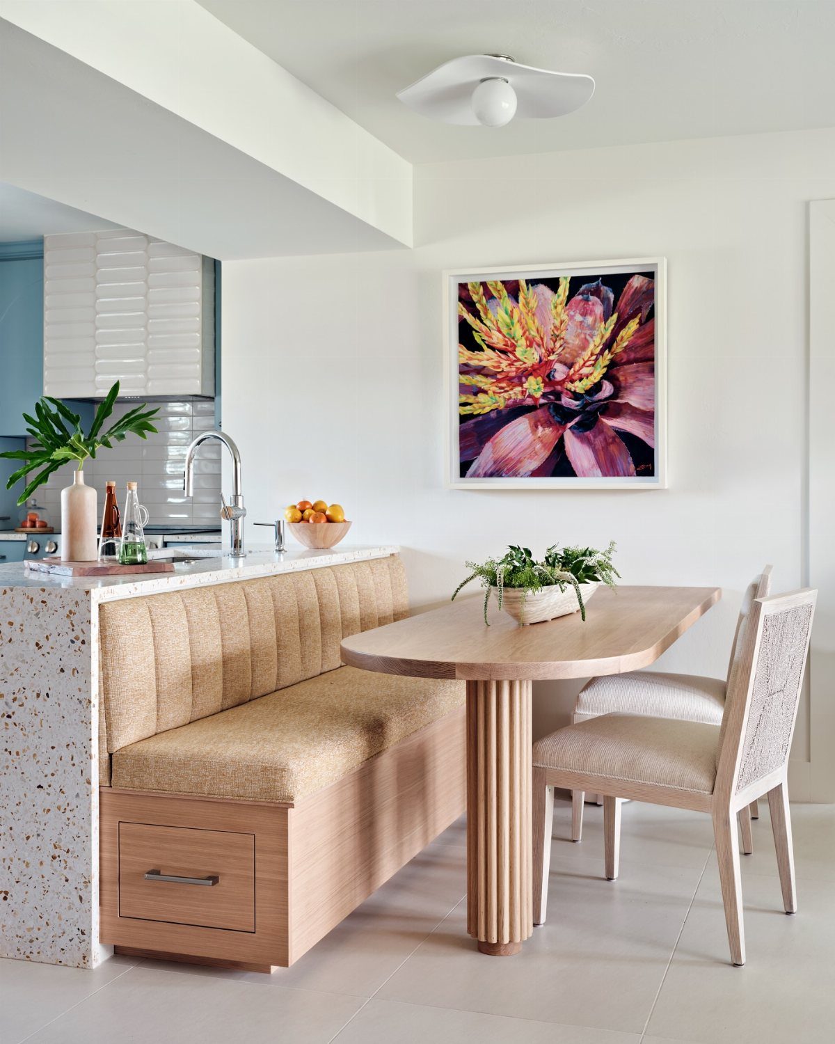 Built-in tan banquette seating with a wooden drawer next to a light wood dining table.