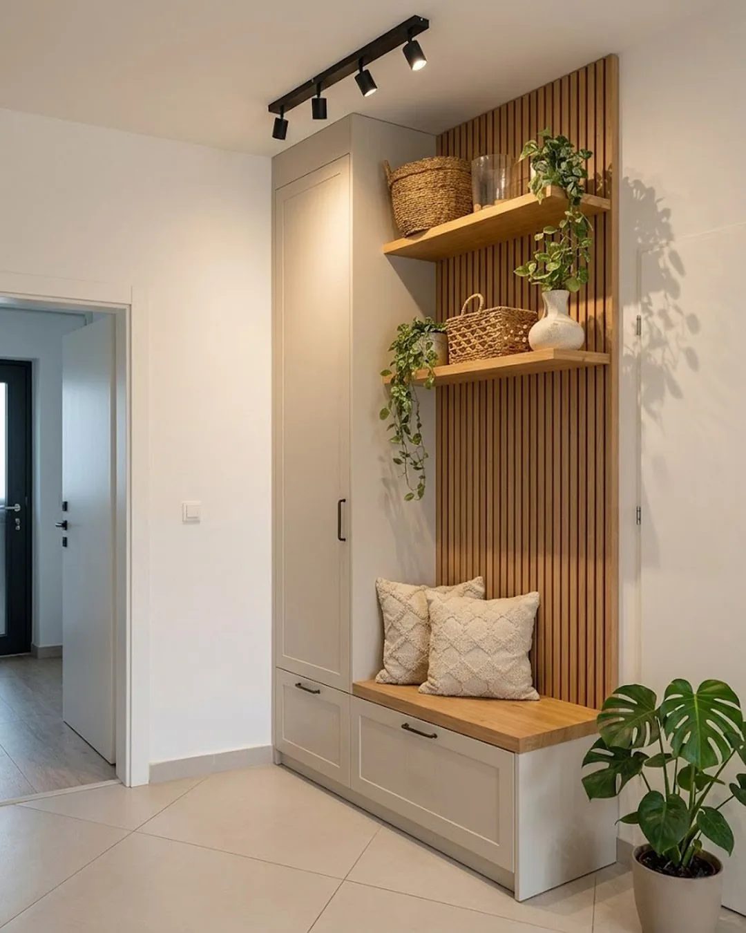 Built-in mudroom storage unit with a wooden bench, drawers, tall cabinet, and decorative wooden wall slats.