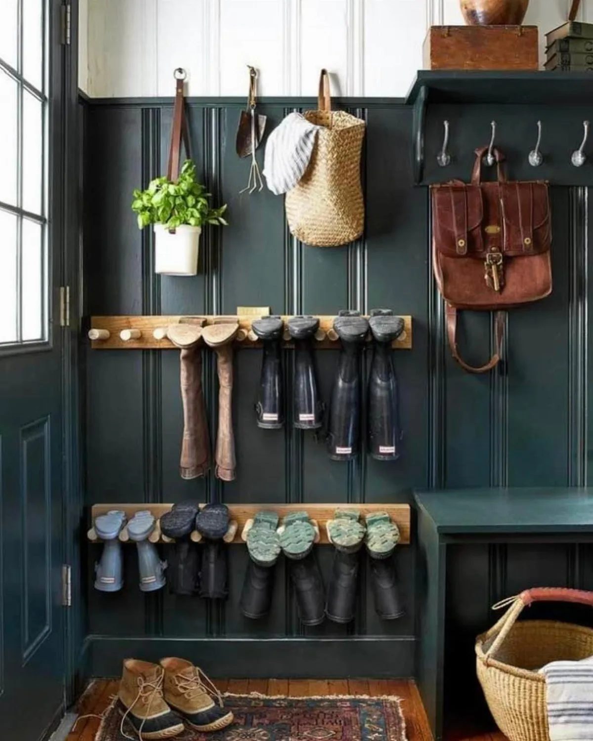 Various boots and shoes hanging from wooden racks on a dark green paneled wall.