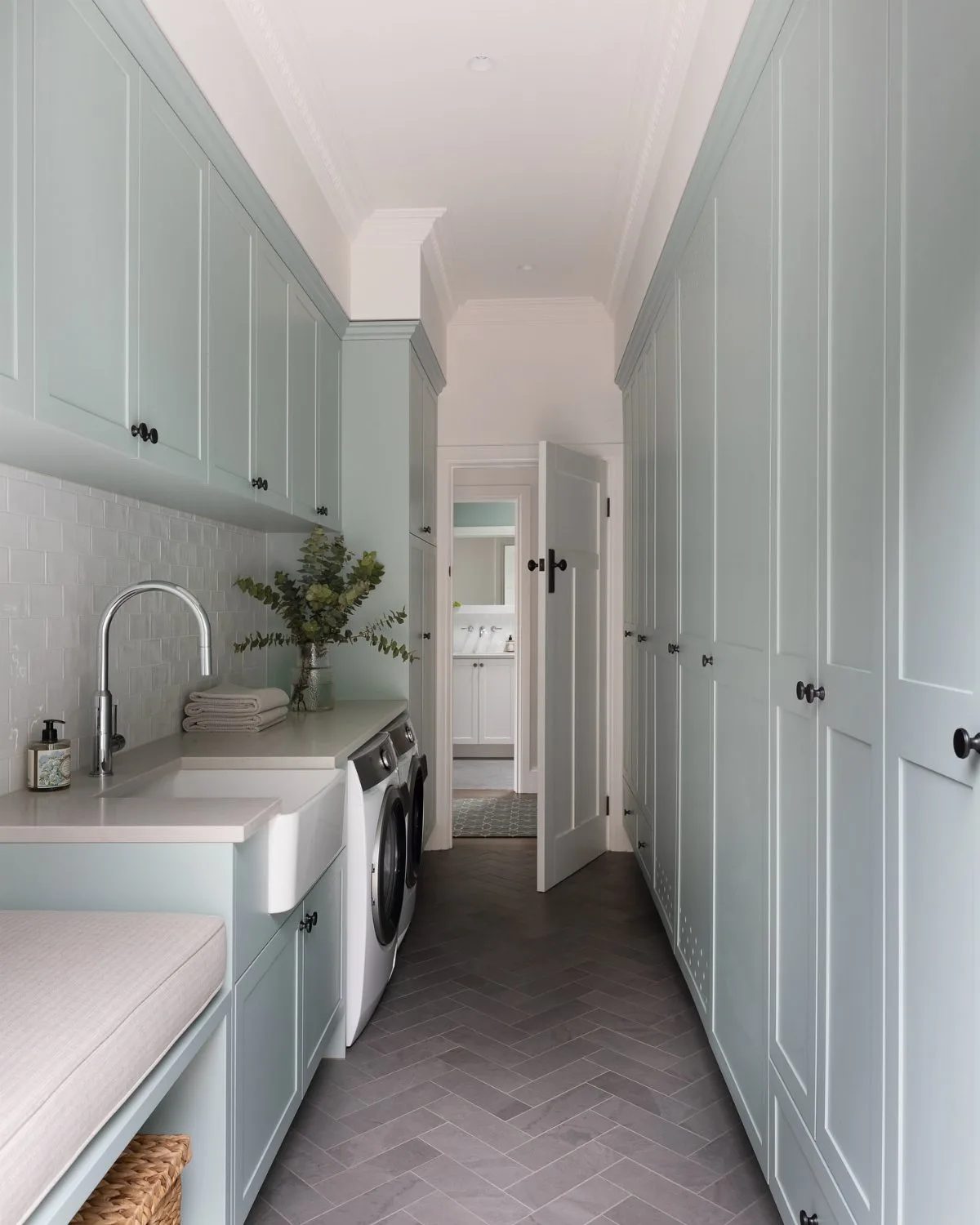 Light blue cabinetry and a white washing machine in a narrow laundry room.