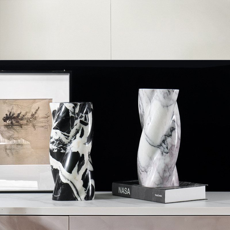 Two twisted marble vases, one black and one white, resting on a white shelf.