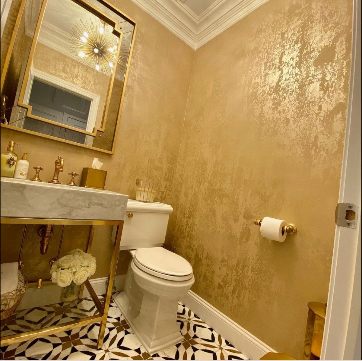 Gold metallic textured wallpaper and gold bathroom fixtures in a luxury bathroom setting.