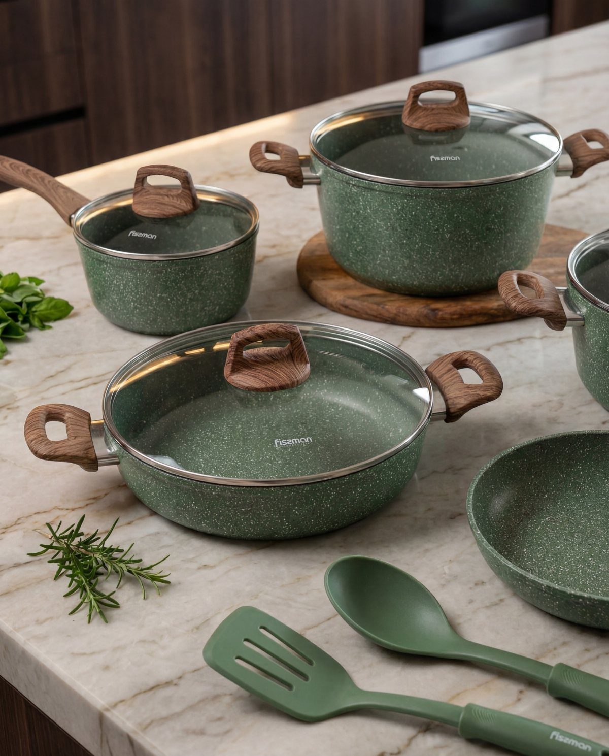Green speckled granite cookware set with wooden handles on a white marble countertop.