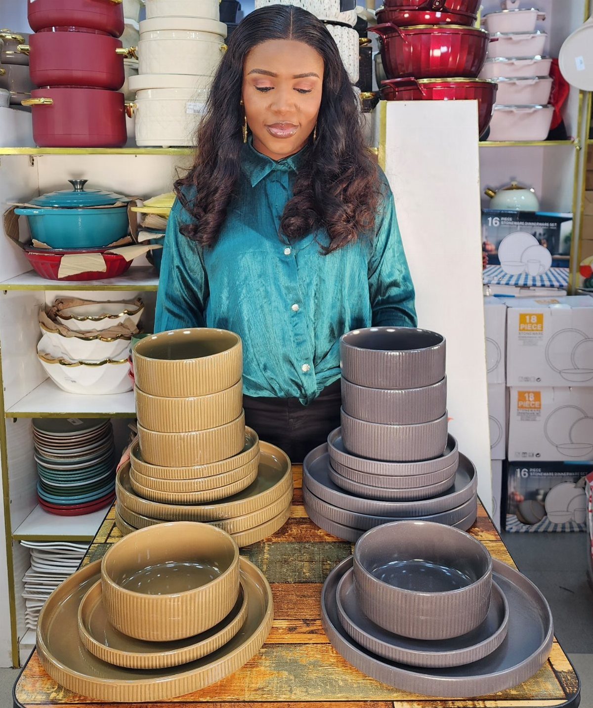 Stacks of tan and grey stoneware plates and bowls displayed on a wooden table.