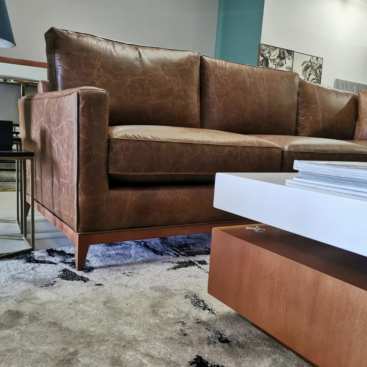 A brown distressed leather sofa positioned in a modern living room with a patterned rug.