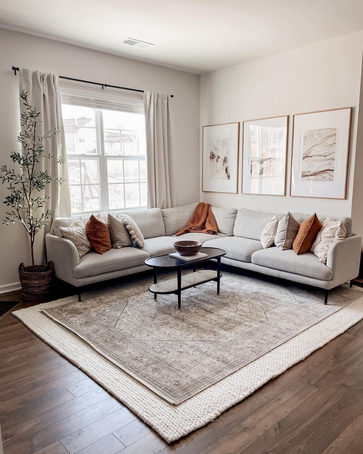 Layered neutral rugs placed on dark wood flooring in a modern living room setting.