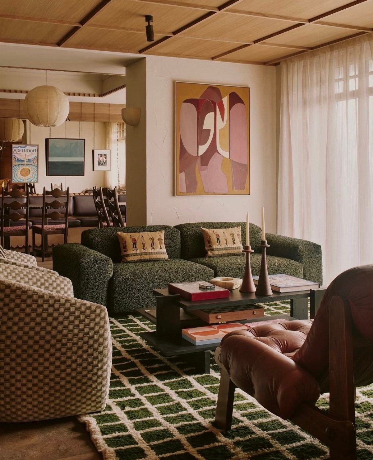 Green textured sofa with patterned pillows and a checkered armchair in a western living room.