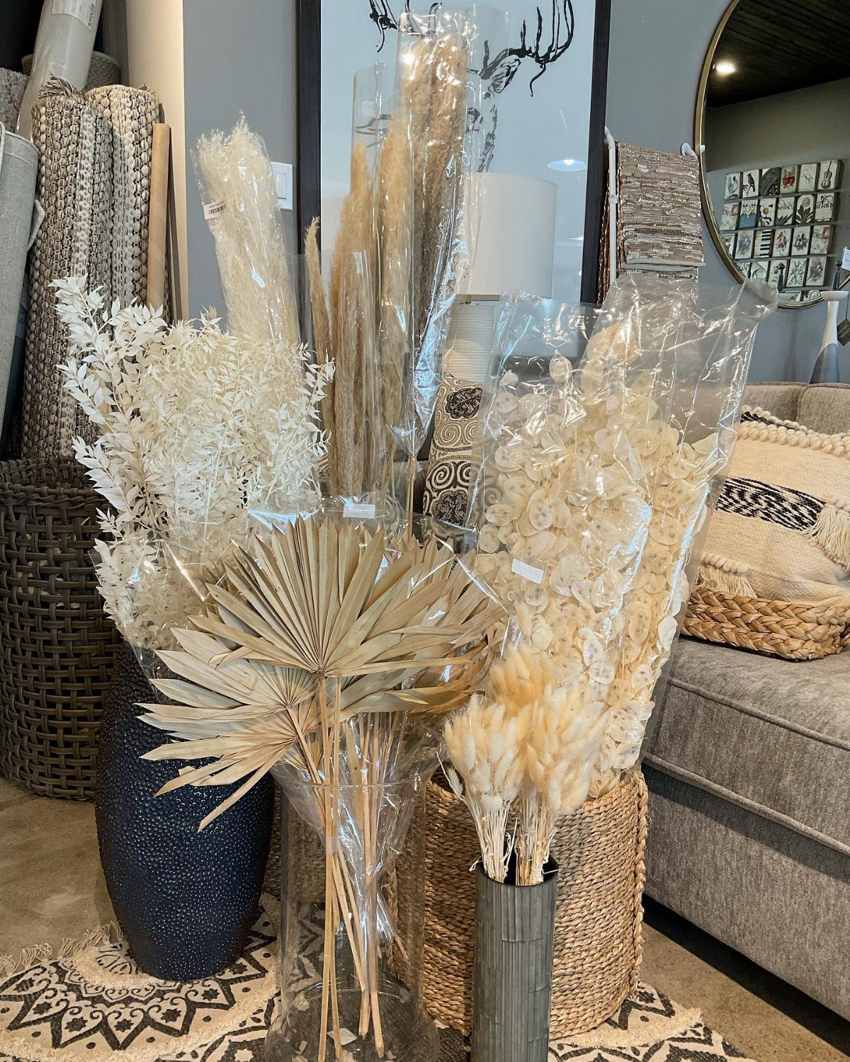 Dried pampas grass and bleached botanical arrangements in vases and woven baskets.