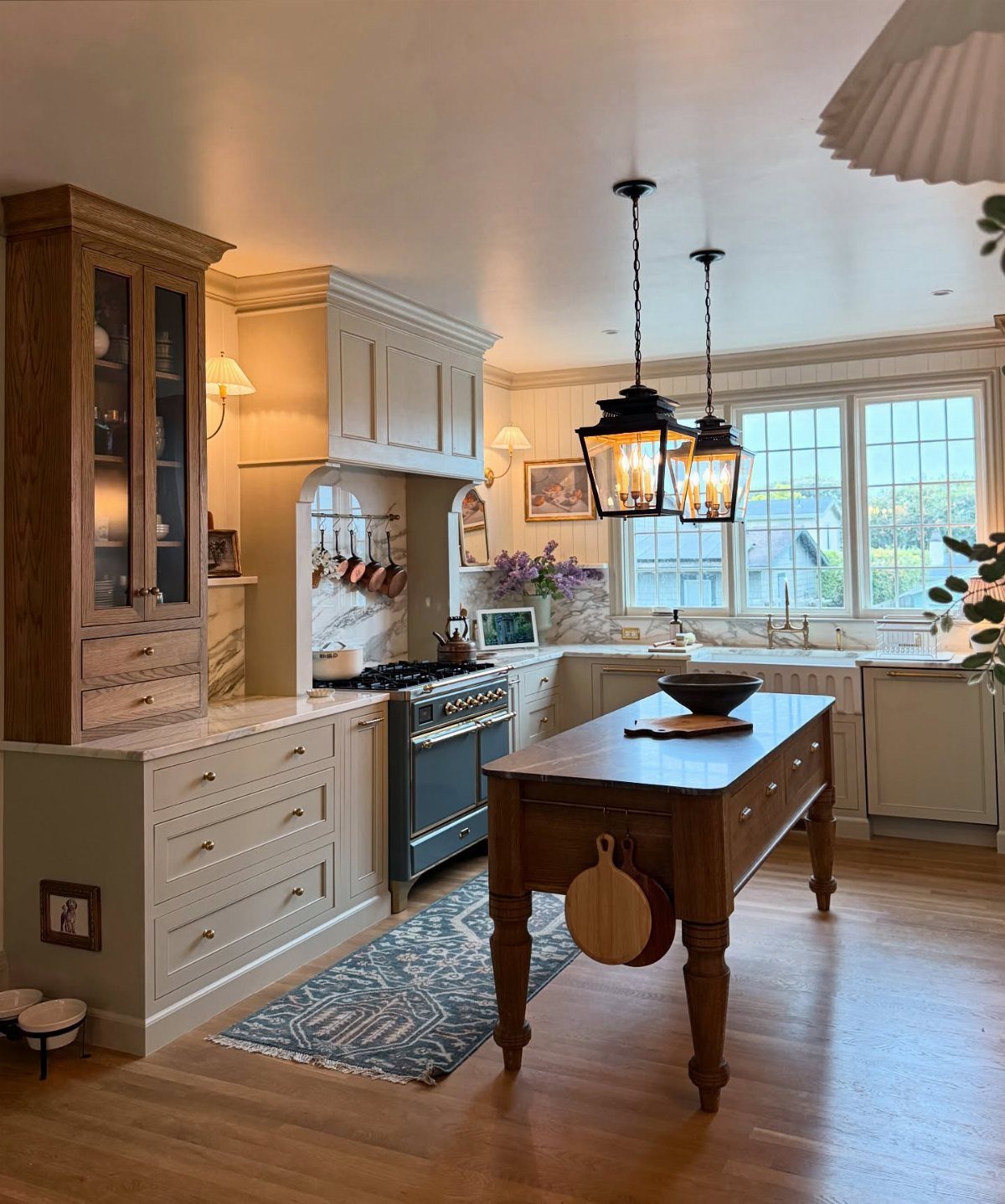 Cream cabinetry and a wooden island in a traditional kitchen with a stone arch.
