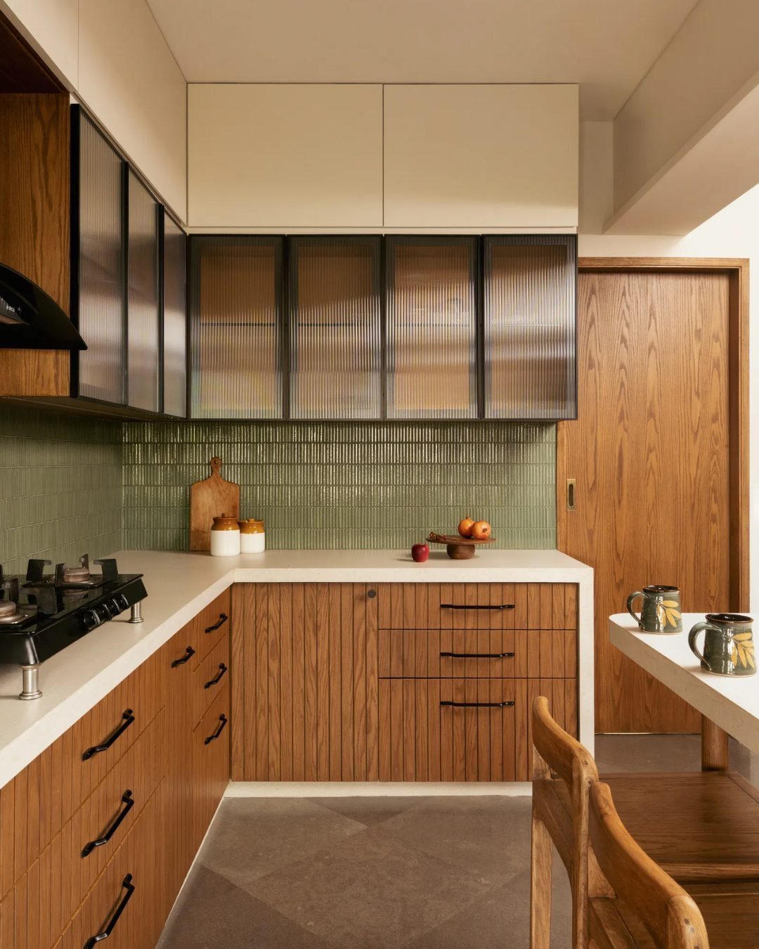Modern kitchen with wood lower cabinets, white countertops, and a green tiled backsplash.