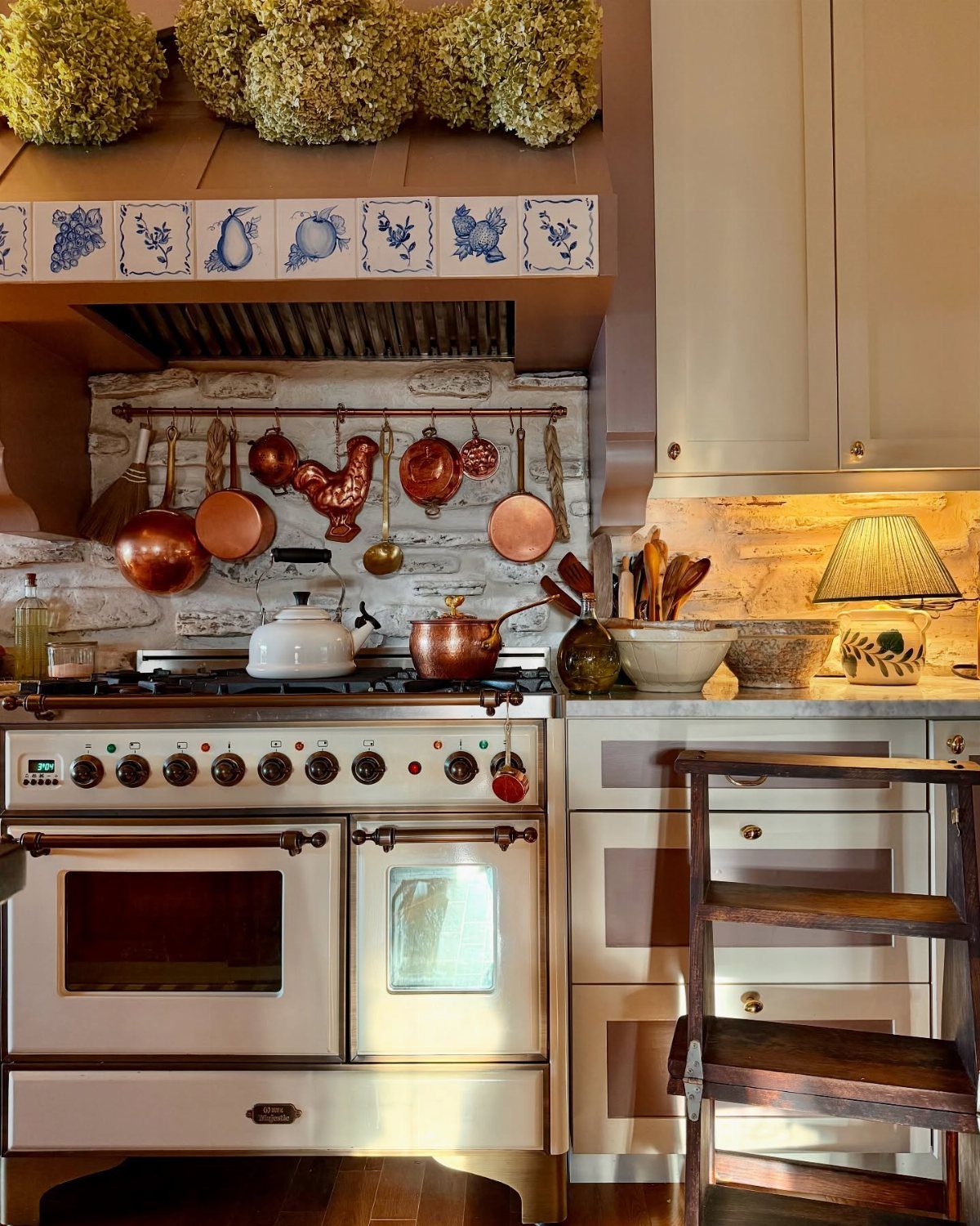 Vintage white stove with copper cookware and a patterned tile backsplash in a rustic kitchen.